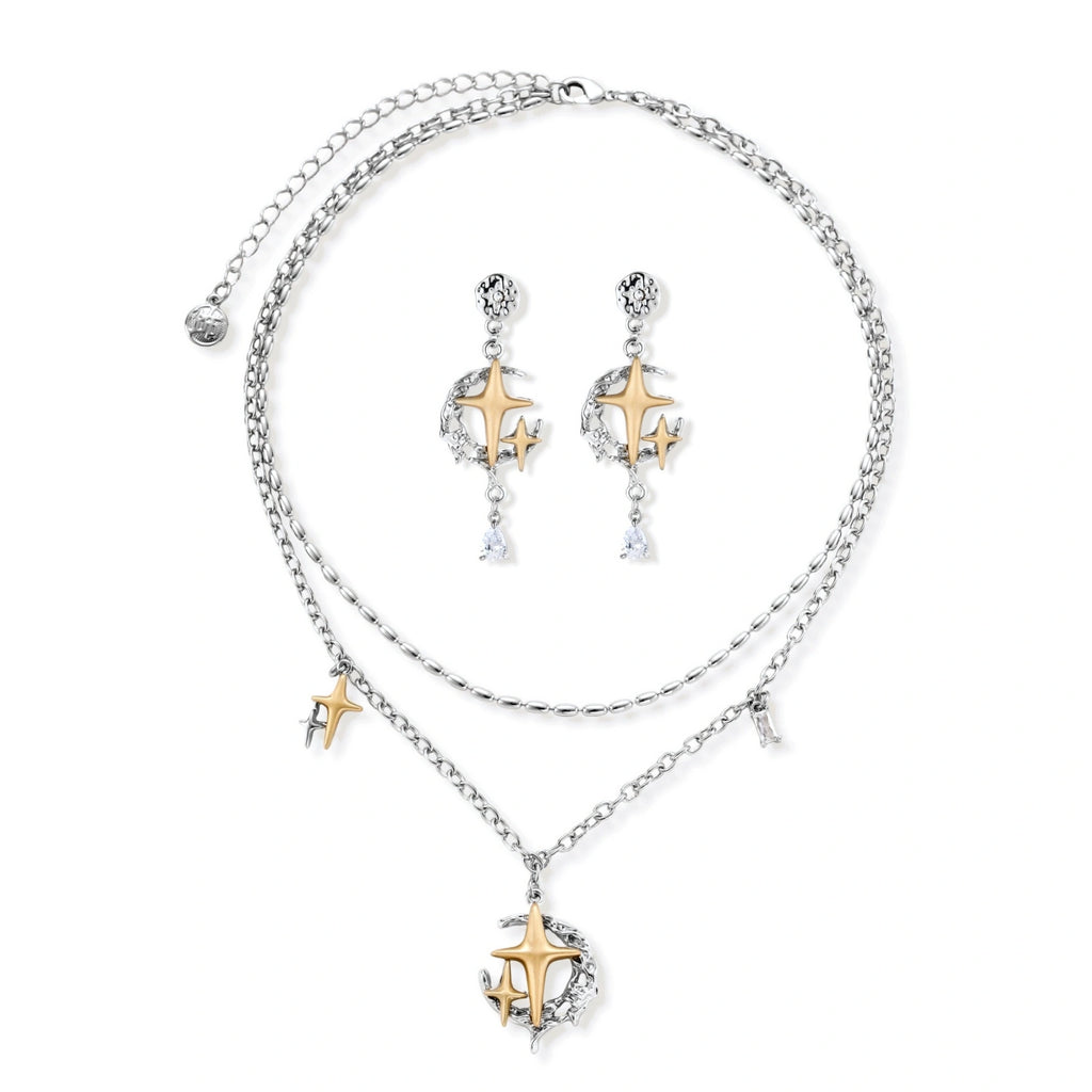 Delicate eco-brass jewelry set featuring gold star and silver moon crescents with clear zirconia crystal drops on cream background