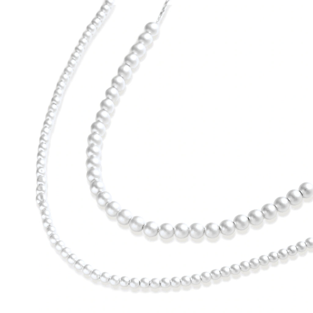 Long sterling silver beaded necklace with graduated sphere design, toggle clasp, and delicate chain extension on white background
