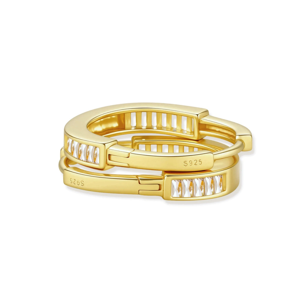 Close-up of gold-plated sterling silver huggie hoop earrings featuring rectangular cubic zirconia stones on neutral background.