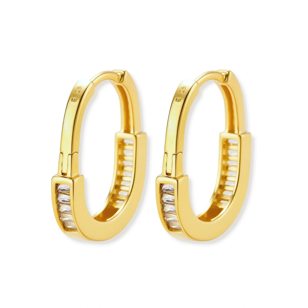 Close-up of gold-plated sterling silver huggie hoop earrings featuring rectangular cubic zirconia stones on neutral background.
